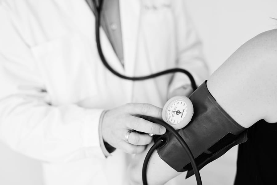 A doctor measuring a patient’s blood pressure, black-and-white photo