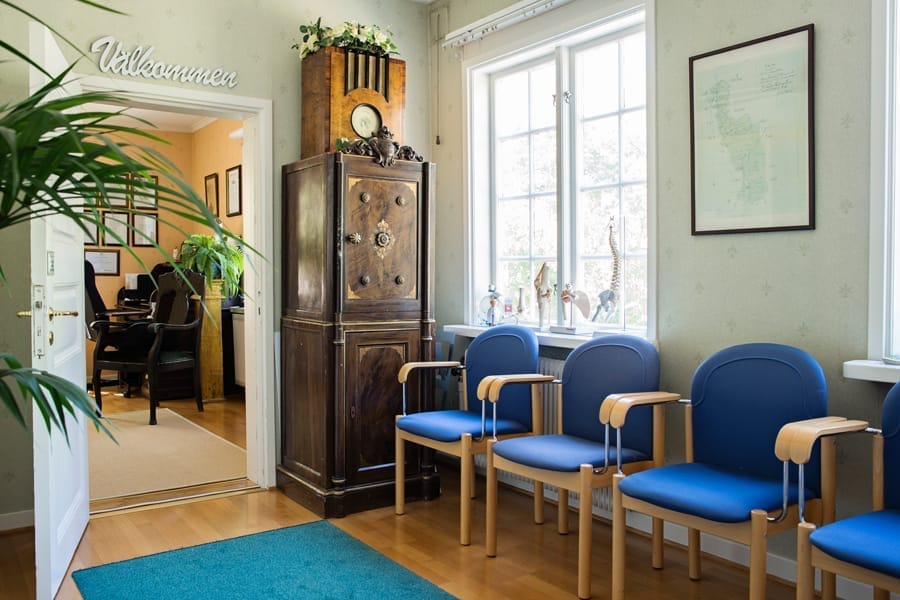The waiting room at Prästgårdskliniken with blue chairs and a Welcome sign