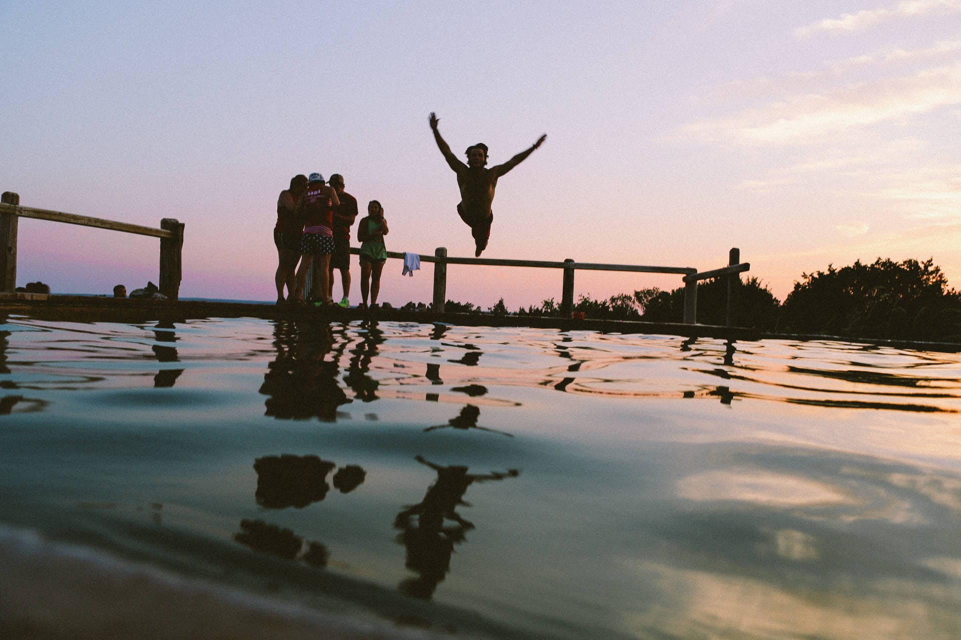 A person jumping from a jetty at sunset